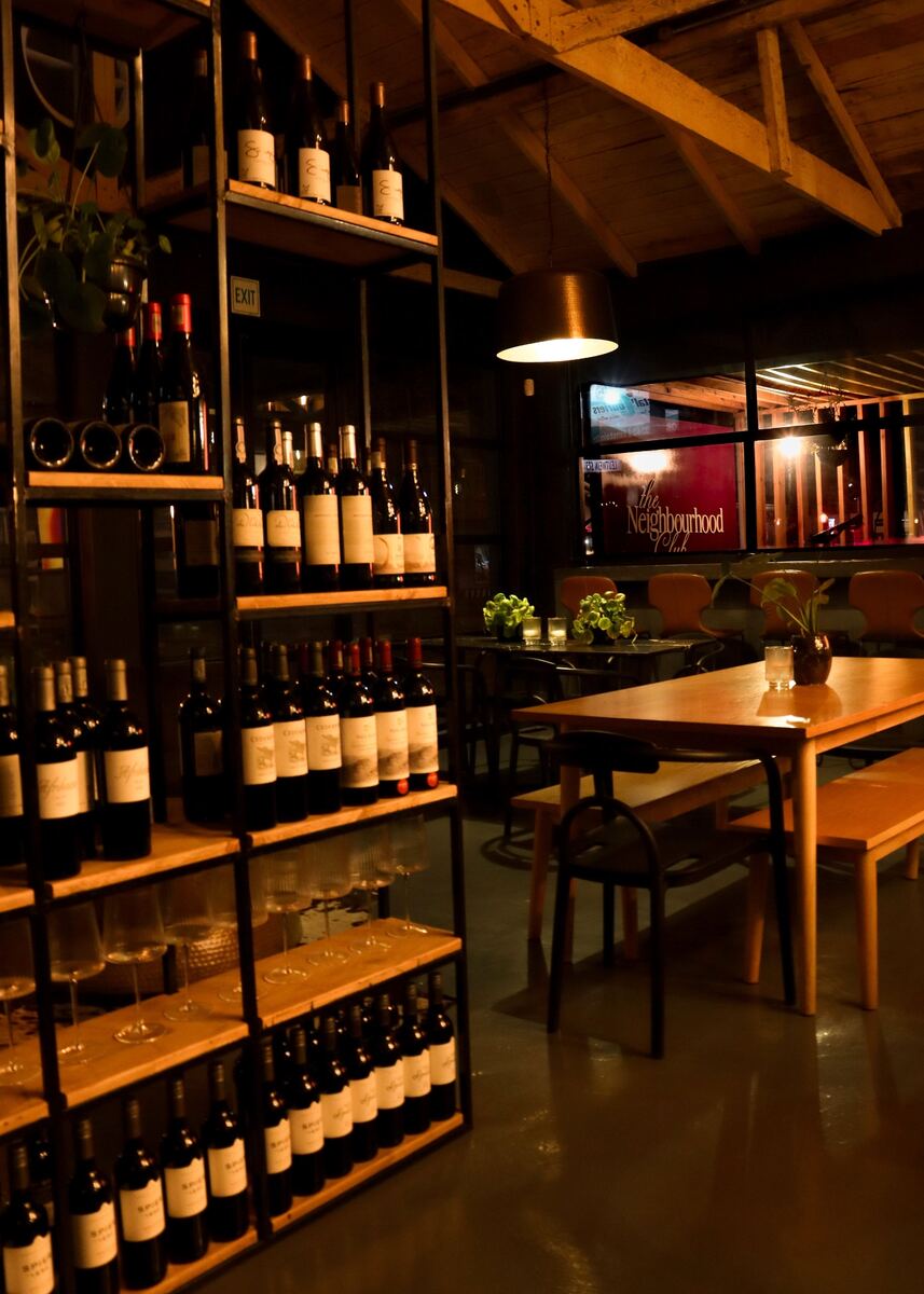 Long timber table and wine shelving in the dimly lit room