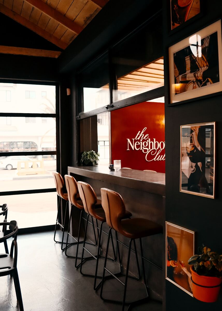 Bar stools and the burgundy club sign by the window